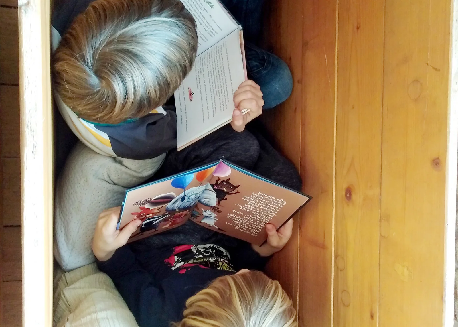 Děti si čtou knížky ve dřevěném zákoutí třídy