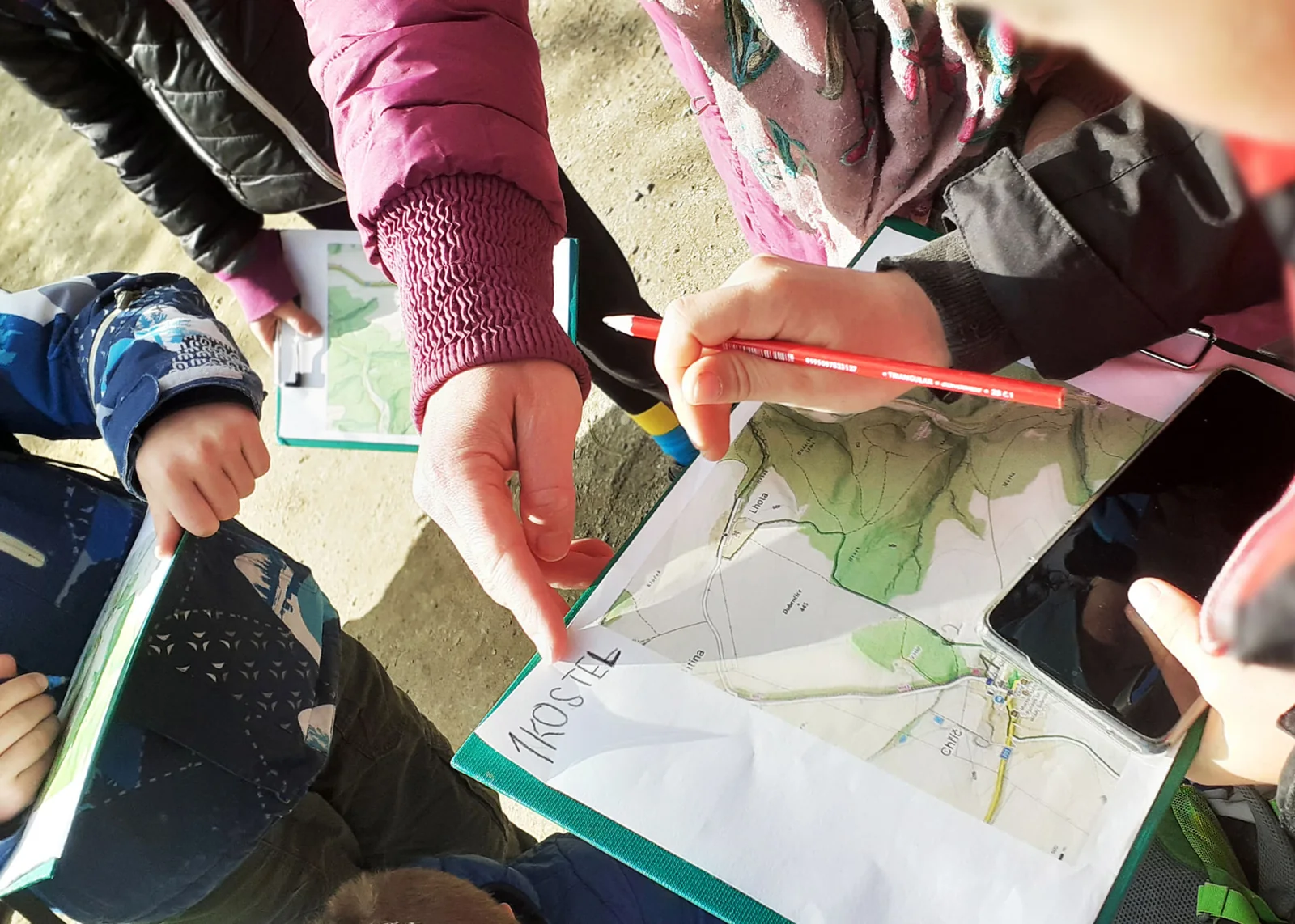 Ruka s tužkou ukazuje na nápis Kostel na mapě v sešitě